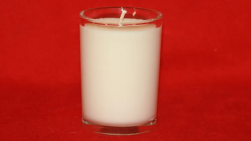 Unlit white soy candle in a clear glass container with a single cotton wick