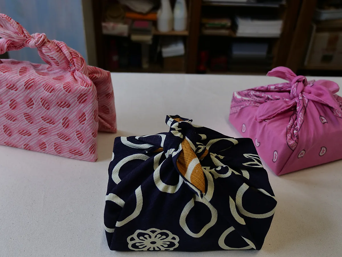 Three parcels wrapped in patterned cloth with knotted tops in the furoshiki style