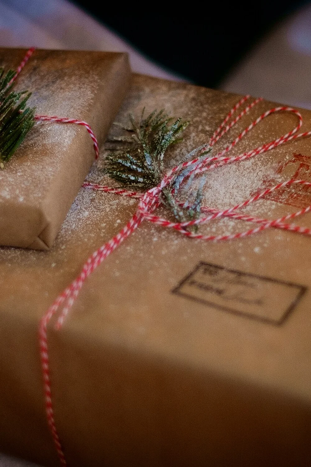 Two kraft paper parcels tied with red and white twine and fir sprigs