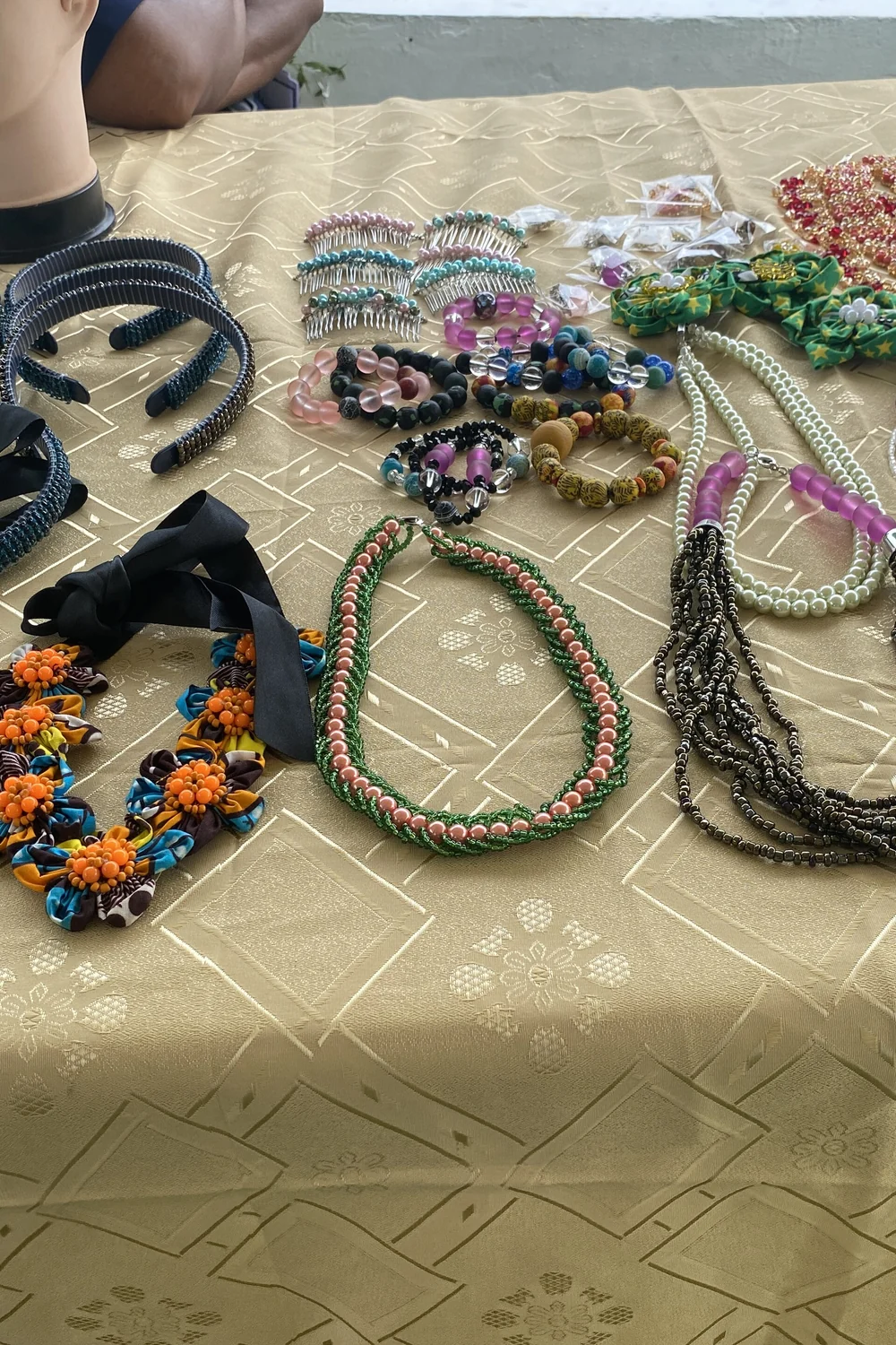 Handmade beaded necklaces and bracelets laid out on a gold cloth