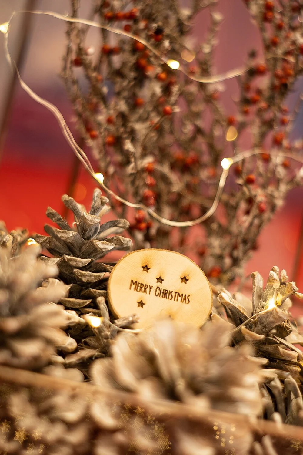 Frosted pinecones and fairy lights arranged inside a glass lantern