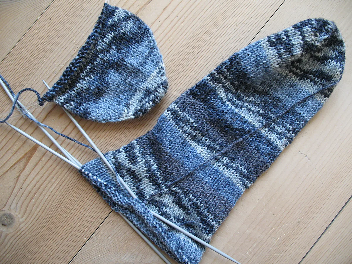 Blue-grey knitted sock and a second one in progress on double-pointed needles