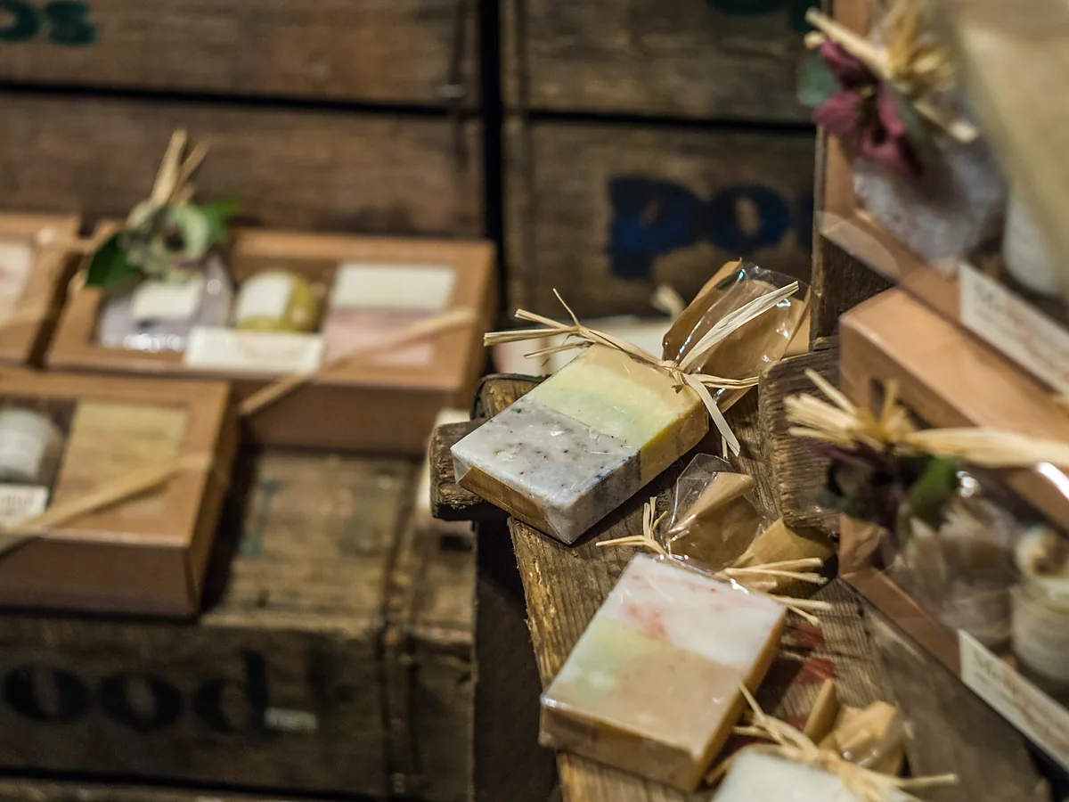Handmade soap bars wrapped in cellophane and tied with raffia on wooden crates