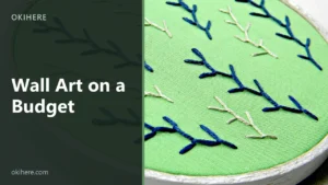Hand-embroidered hoop art with blue and cream feather stitch on green fabric, with the title Wall Art on a Budget overlaid